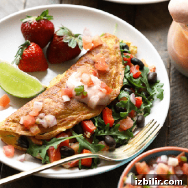 A plate of omelet with black beans, strawberries and salsa.