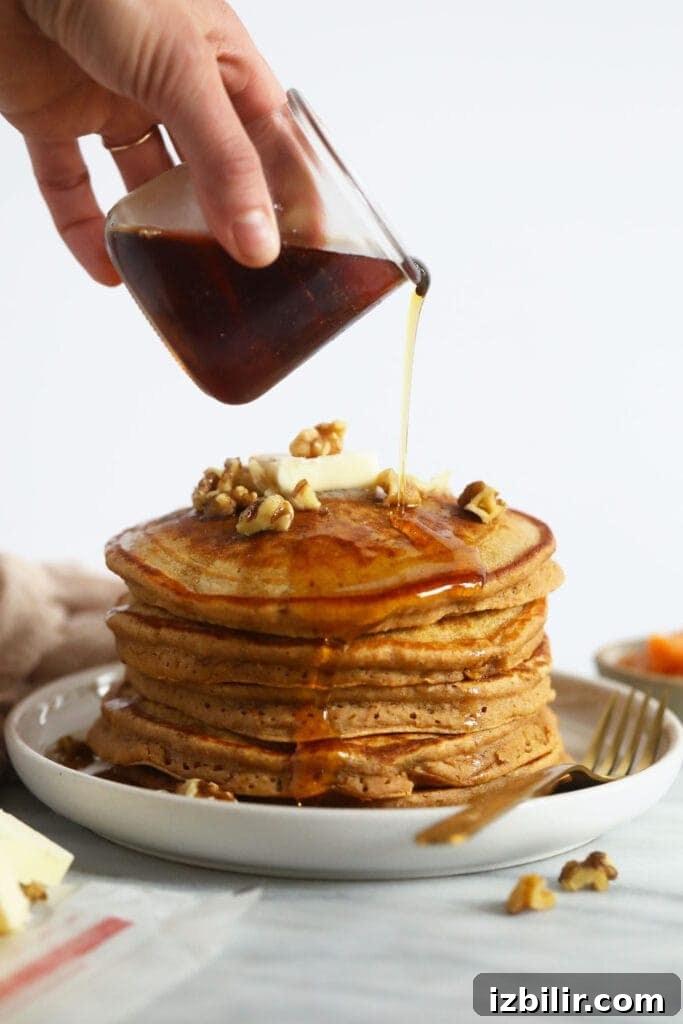 Fluffy Sweet Potato Pancakes Recipe 6 Pouring maple syrup over sweet potato pancakes.