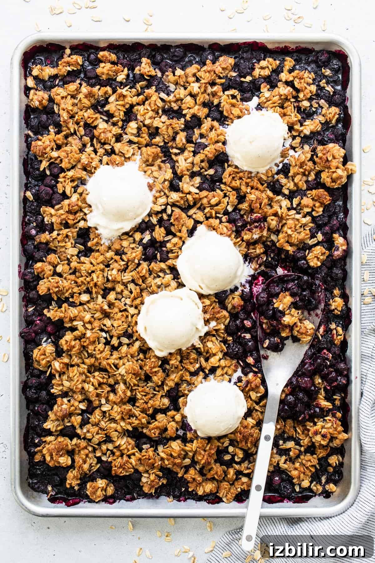 Sheet Pan Blueberry Crisp Recipe 2 Freshly baked blueberry crumble with scoops of vanilla ice cream on top.