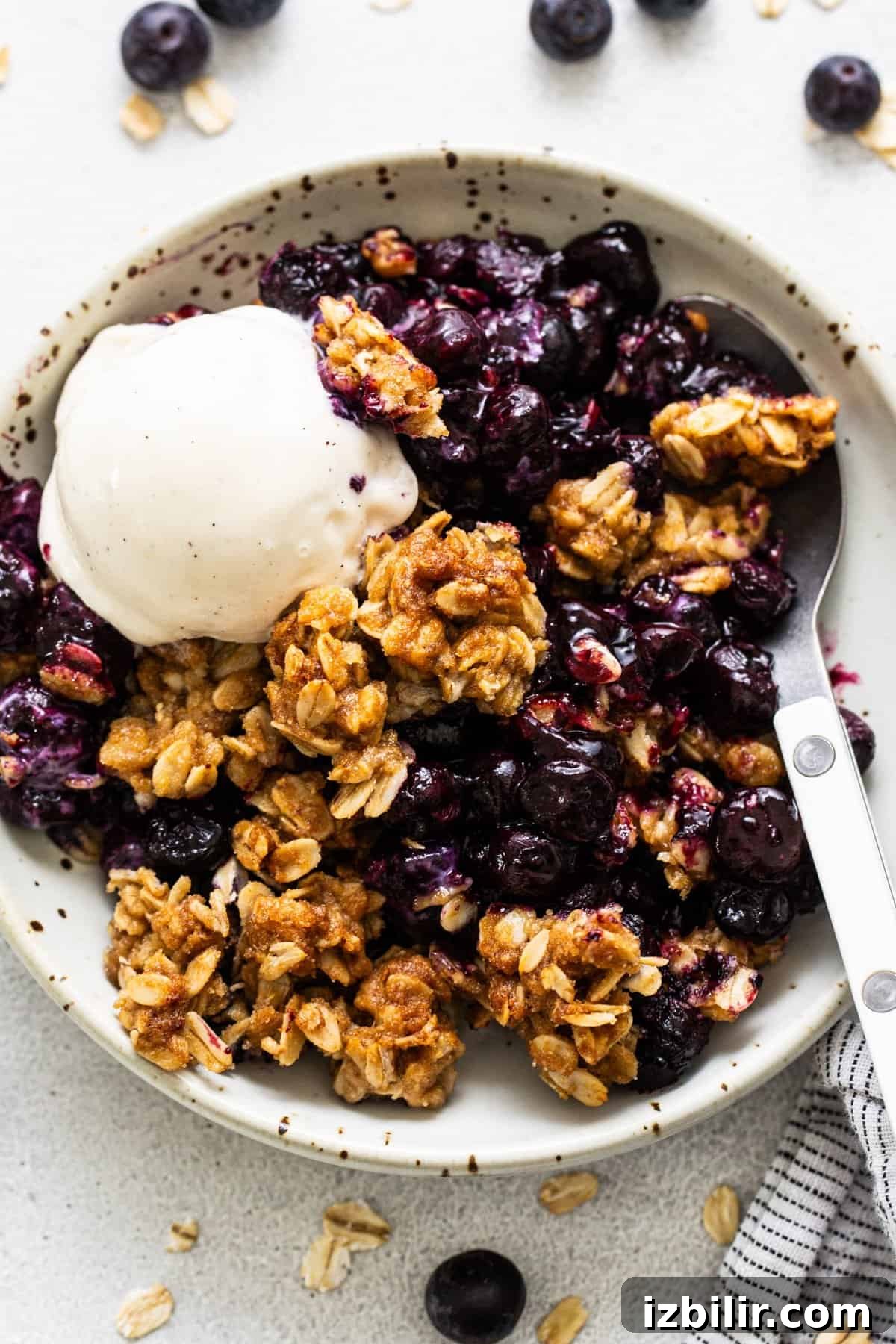 Sheet Pan Blueberry Crisp Recipe 6 A bowl of blueberry crumble topped with a scoop of vanilla ice cream.