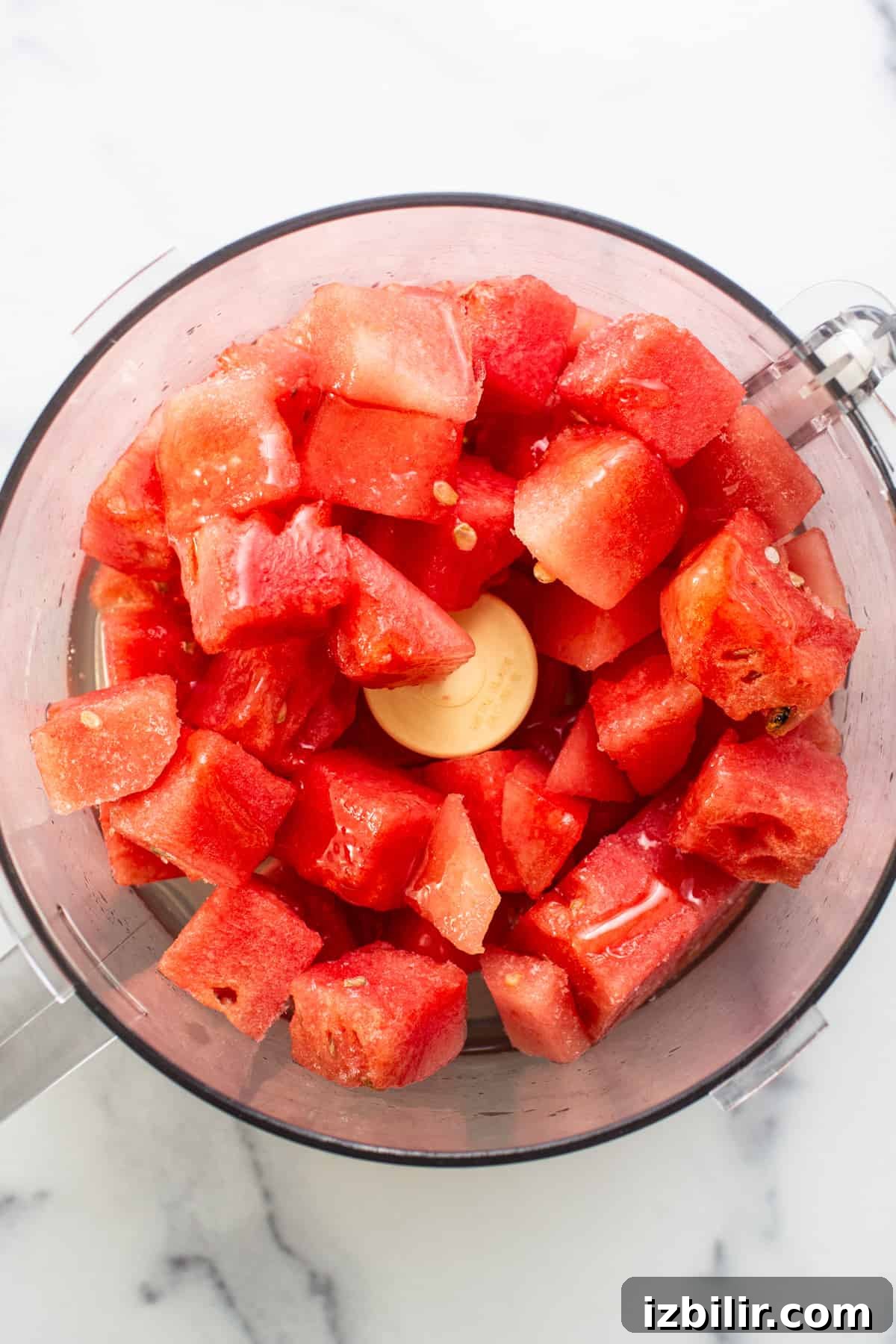 Chunks of fresh red watermelon in a food processor, ready for blending.