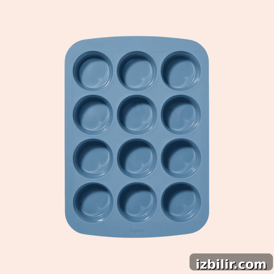 A blue silicone muffin tray with twelve round molds arranged in a three-by-four grid against a light background.