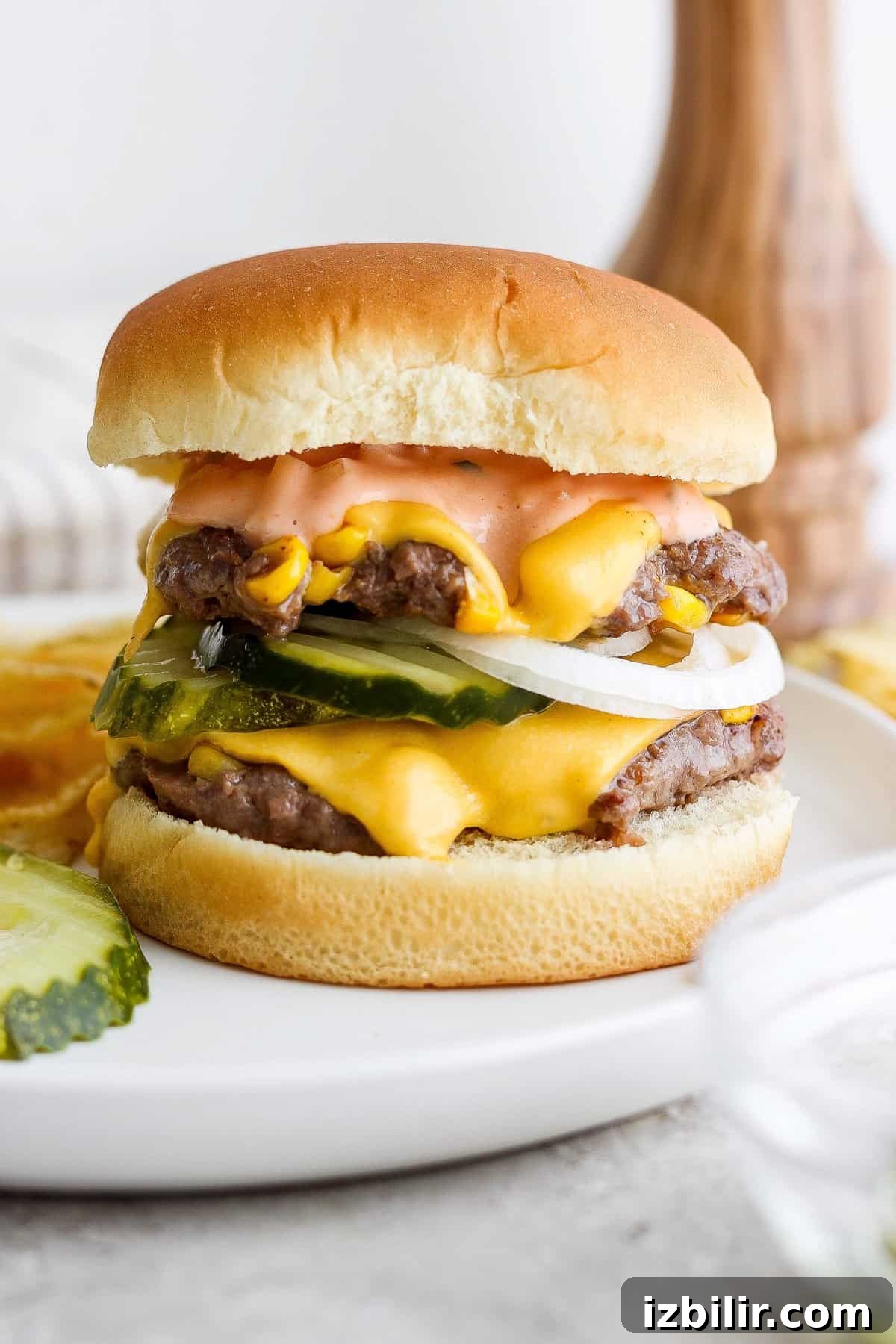 Loaded Sweet Corn Smash Burger Recipe 2 Double cheeseburger with pickles on a white plate.