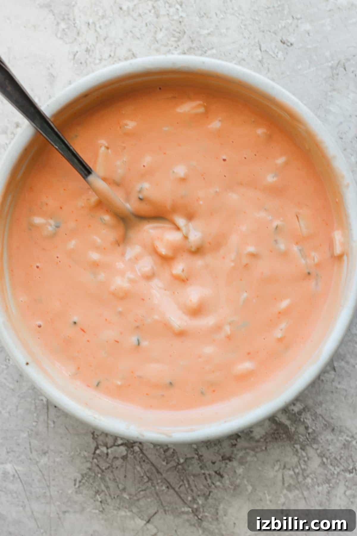Loaded Sweet Corn Smash Burger Recipe 3 A bowl of creamy tomato soup with herbs, served with a spoon.