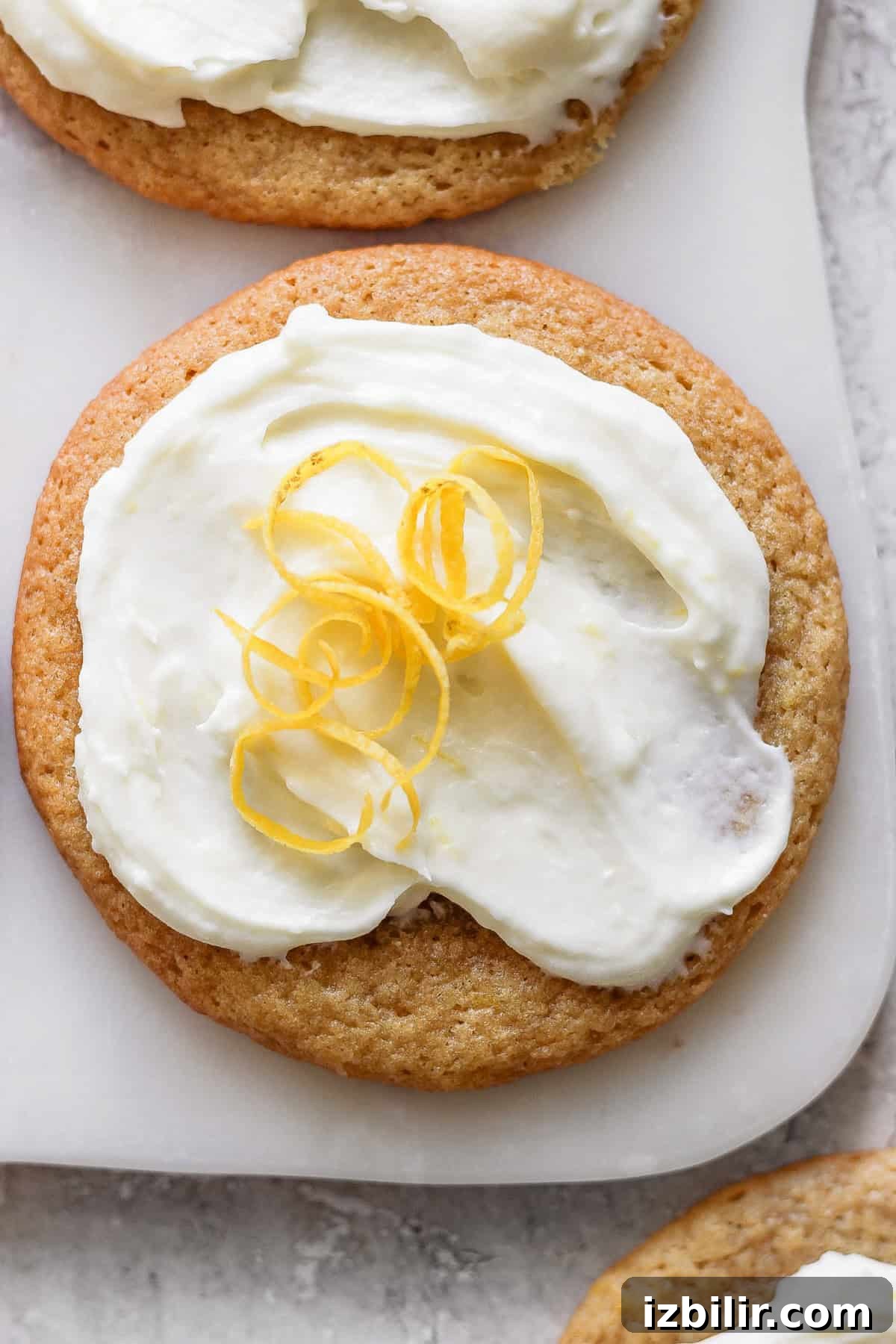 Zesty Lemon Cookies with Cream Cheese Frosting 4 A lemon cookie adorned with cream cheese frosting and garnished with a twist of lemon peel.