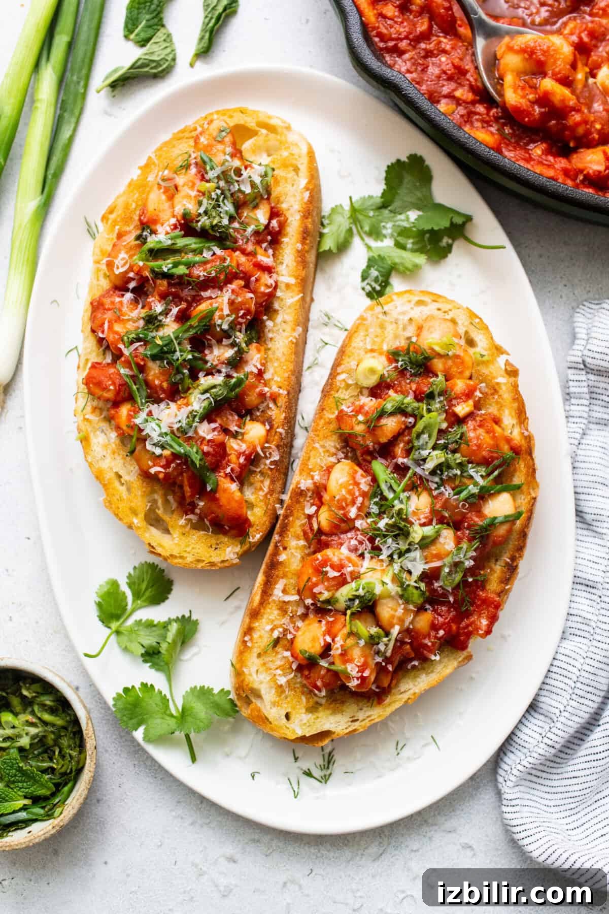 Classic British Beans on Toast Recipe 2 Two slices of bread with tomato sauce and herbs on a plate.