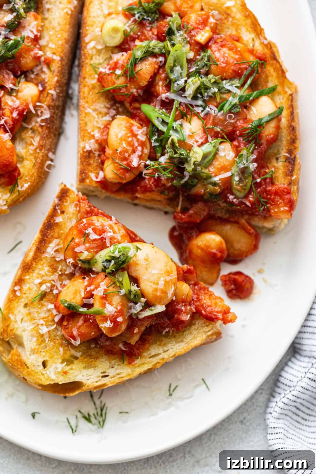 Classic British Beans on Toast Recipe 7 Two slices of toast with tomatoes and herbs on a plate.