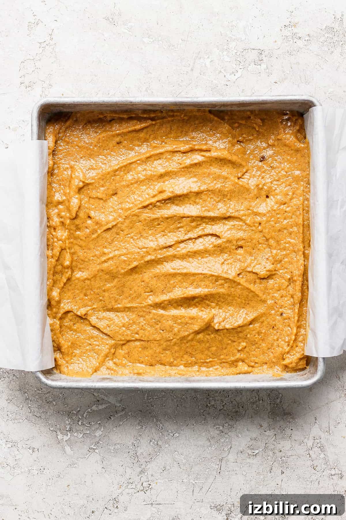 Pumpkin Coffee Cake with Cinnamon Streusel 4 Square baking pan filled with unbaked pumpkin batter lined with parchment paper.