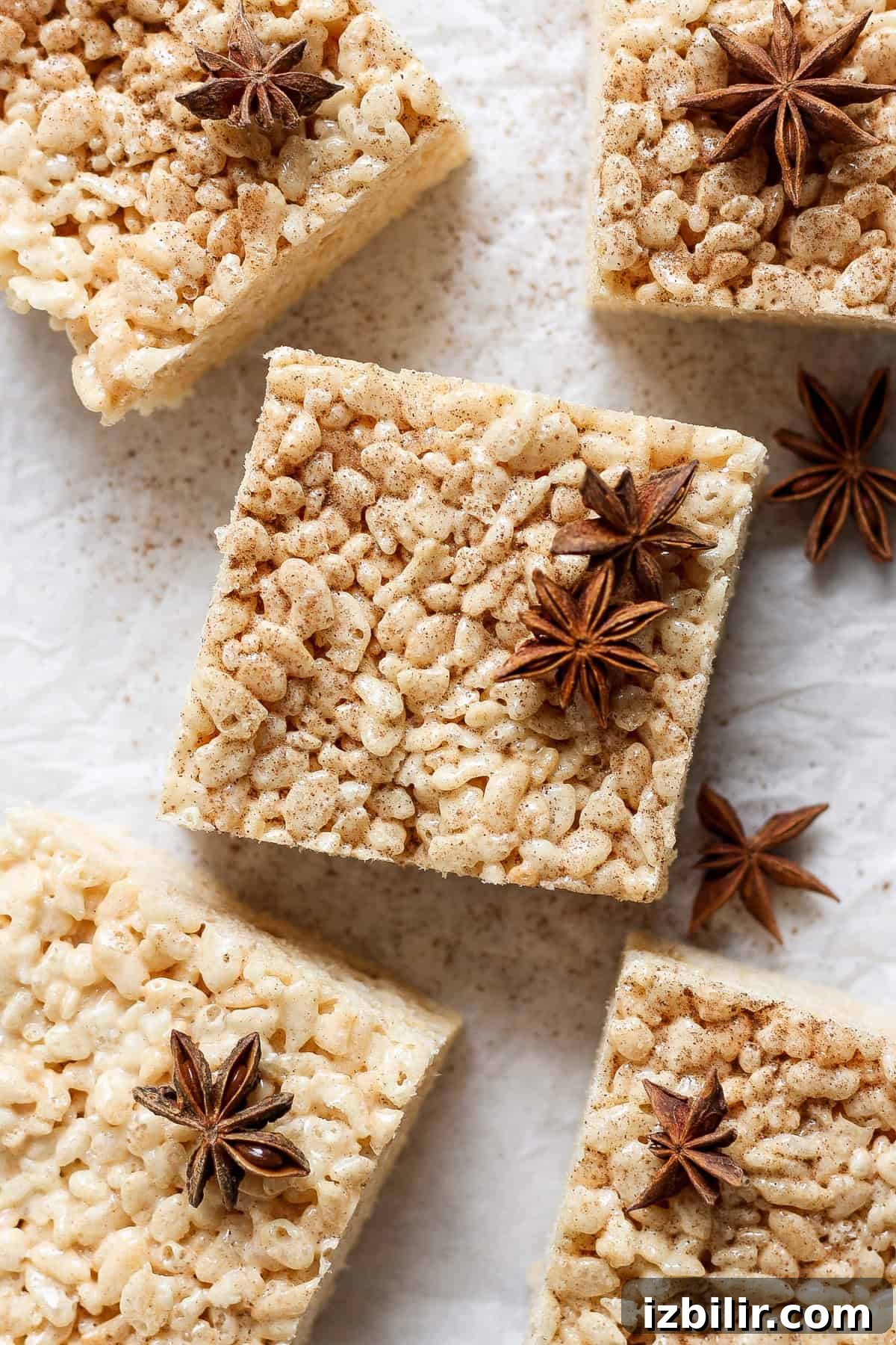Brown Butter Chai Rice Krispie Treats Recipe 2 Square rice crispy treats with a dusting of spices and garnished with star anise, arranged on a parchment paper surface.