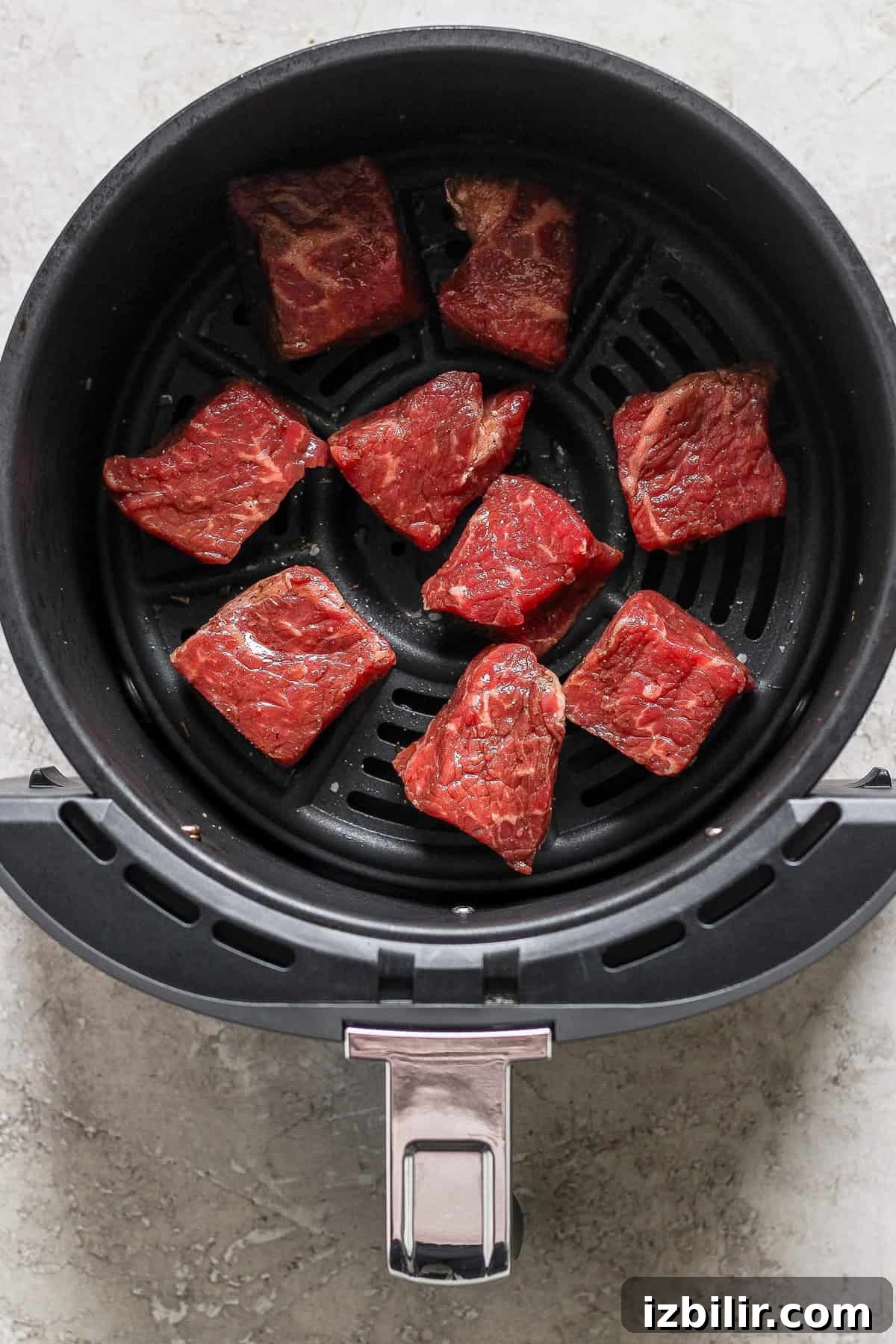 Fit Foodie Cooking Club: September 2024 Seasonal Recipes 3 Raw beef pieces arranged in an air fryer basket, ready for cooking.