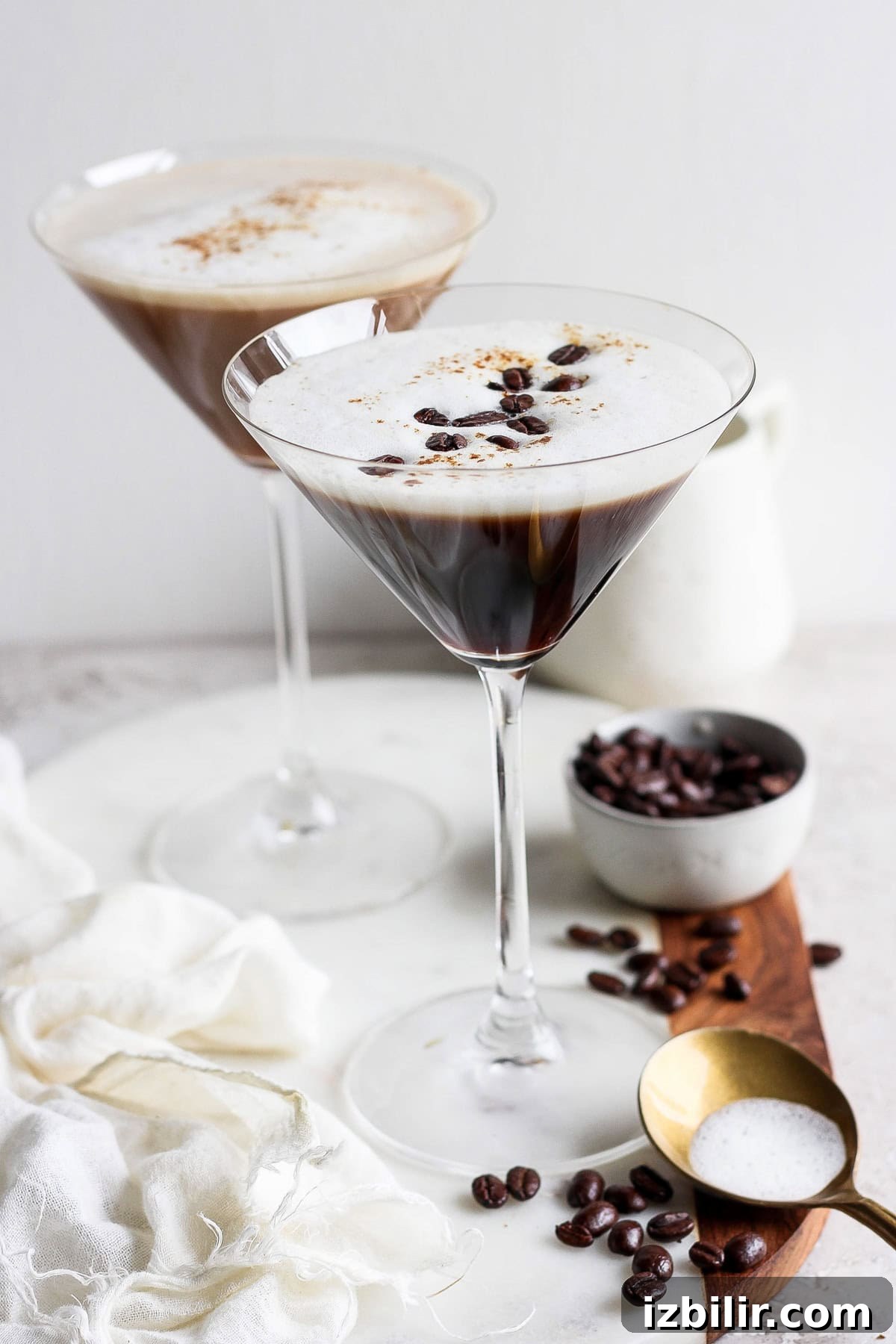 Brown Sugar Shaken Espresso Martini Recipe 2 Two espresso martinis in martini glasses, garnished with coffee beans, on a wooden board