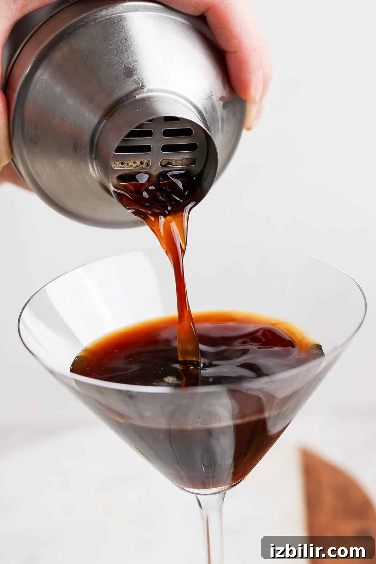 Brown Sugar Shaken Espresso Martini Recipe 4 Pouring dark liquid from a metal shaker into a martini glass