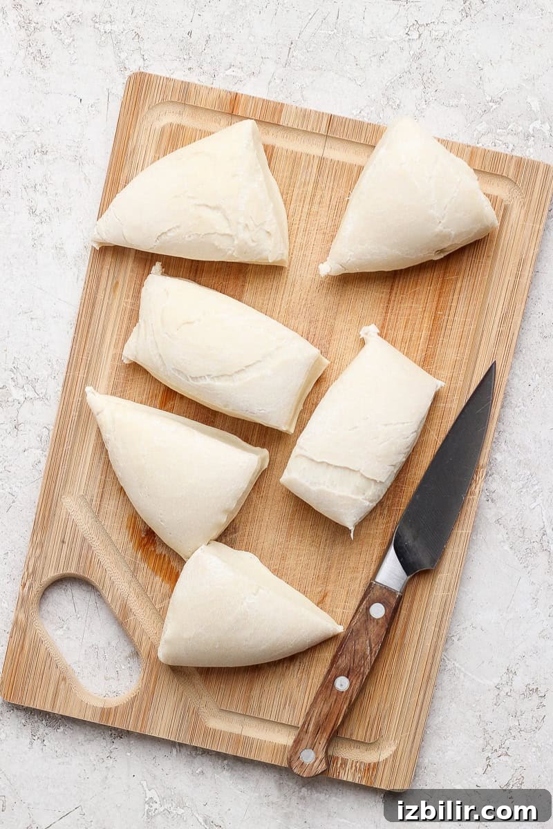 Nonna Marie's Pizza Fritta Recipe: Crispy Italian Fried Pizza 4 Sliced triangles of dough are arranged on a wooden cutting board with a knife.