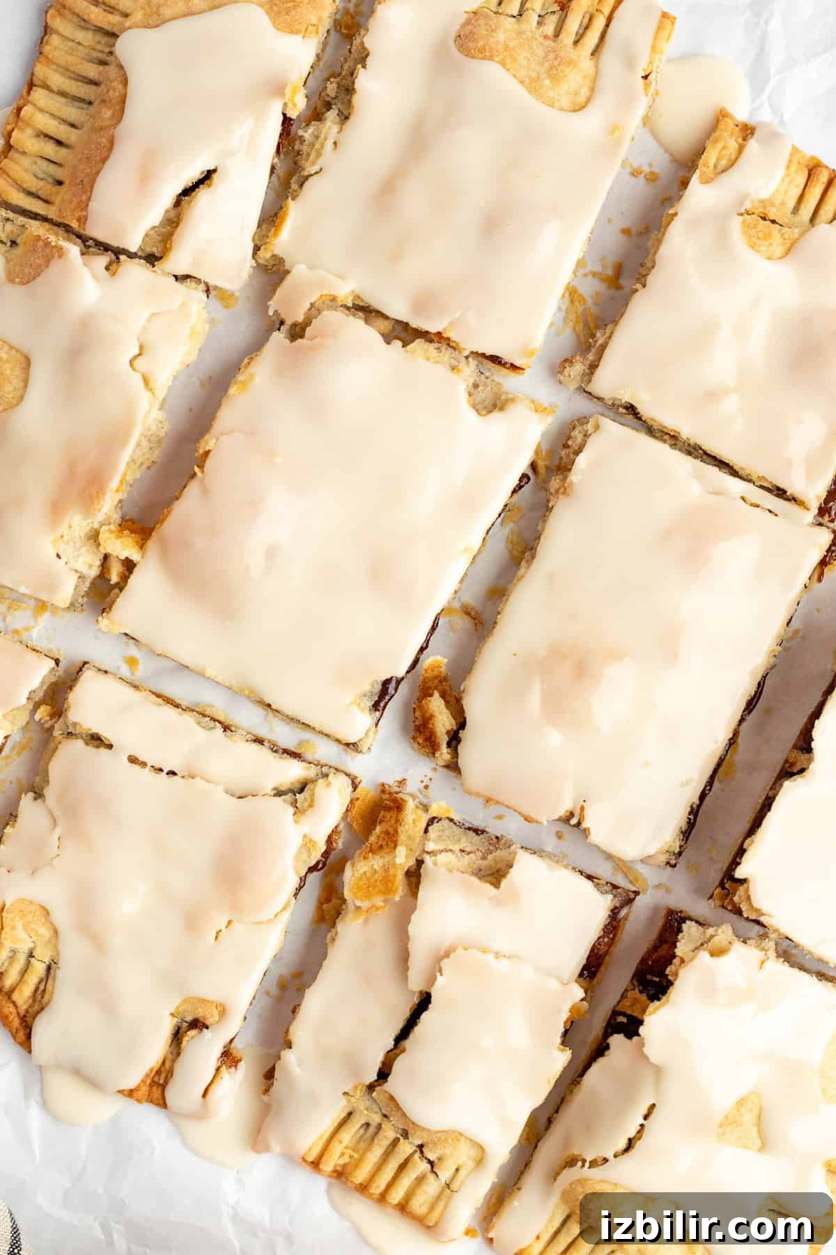 Homemade Protein Pop Tarts Recipe 2 Rectangular pastries covered with a light beige icing are arranged in a 3x4 grid on a sheet of parchment paper.
