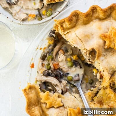 A chicken pot pie on a plate with a slice taken out.