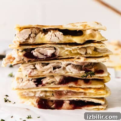 A stack of leftover Thanksgiving turkey quesadillas with cranberry sauce.