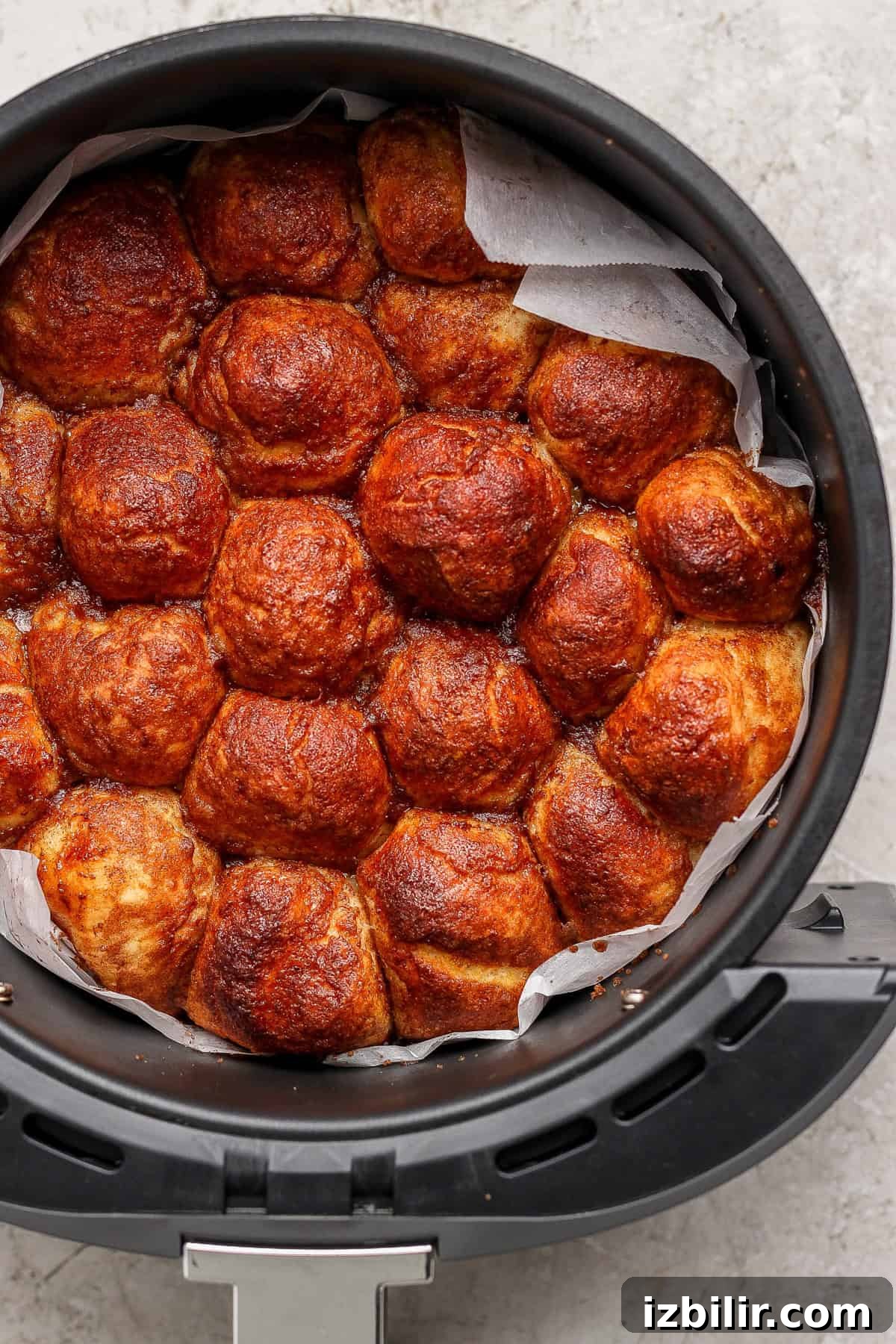 Air Fryer Protein Monkey Bread Recipe 6 Golden brown bread rolls packed tightly in a round container with parchment paper.