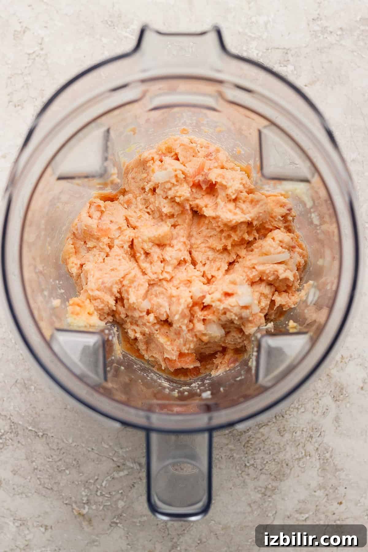 Sesame Ginger Salmon Meatballs with Sticky BBQ Glaze 4 A blender containing a coarse, orange-colored mixture on a light textured surface.