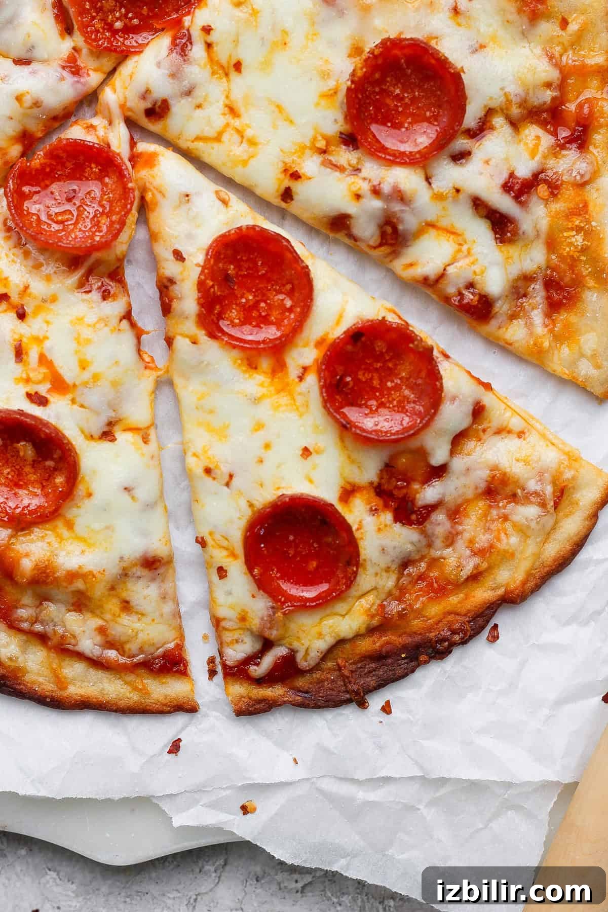 Slices of pepperoni pizza with melted cheese on parchment paper.