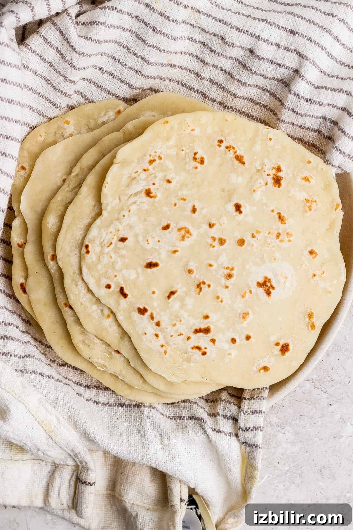 A stack of homemade flatbreads resting on a striped kitchen towel.