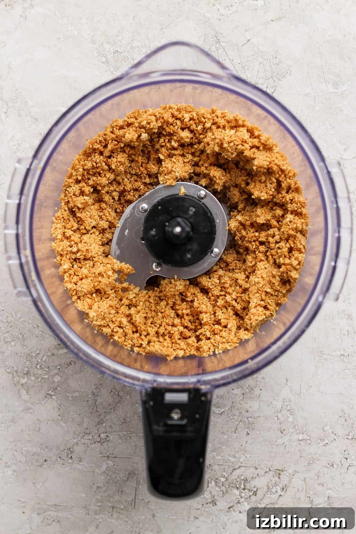 A food processor containing a mixture of finely ground ingredients on a light textured surface.