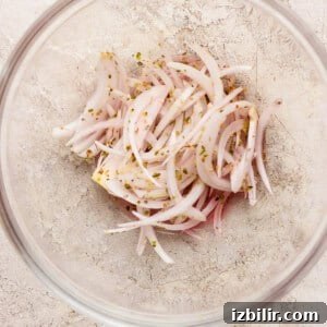 Italian Grinder Sliders Recipe: Classic Mini Italian Sandwiches 7 Thinly sliced onions mixed with vinegar and dried herbs in a clear bowl.