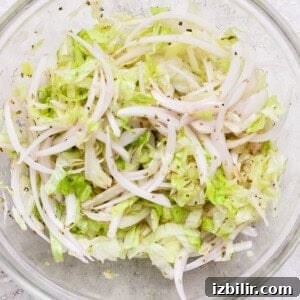 Italian Grinder Sliders Recipe: Classic Mini Italian Sandwiches 8 Shredded lettuce combined with marinated onions and olive oil in a clear bowl.