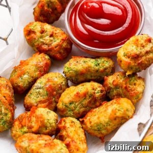 A basket of baked zucchini tots served with a small bowl of ketchup for dipping.