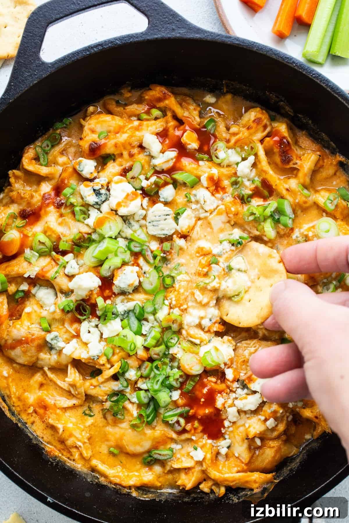 High-Protein Cottage Cheese Recipes for Fall 2 A person dipping into a skillet of buffalo chicken dip.