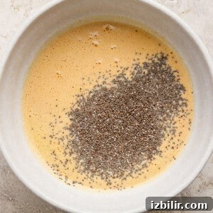 High-Protein Pumpkin Chia Pudding Recipe 7 A white bowl containing whisked mixture with a pile of chia seeds on top.