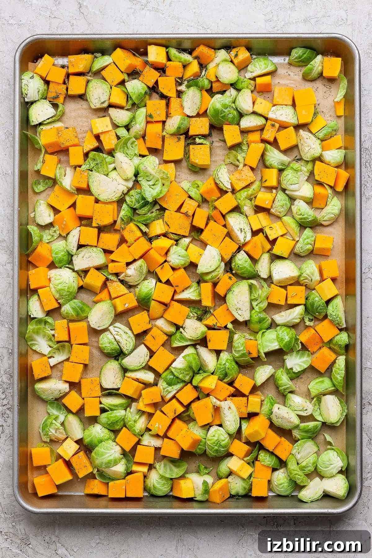 Autumn Couscous Salad Recipe with Seasonal Veggies 3 Cubed butternut squash and halved Brussels sprouts spread on a parchment-lined baking sheet, seasoned with salt, pepper, and herbs—perfect for adding to your favorite couscous salad recipe after roasting.