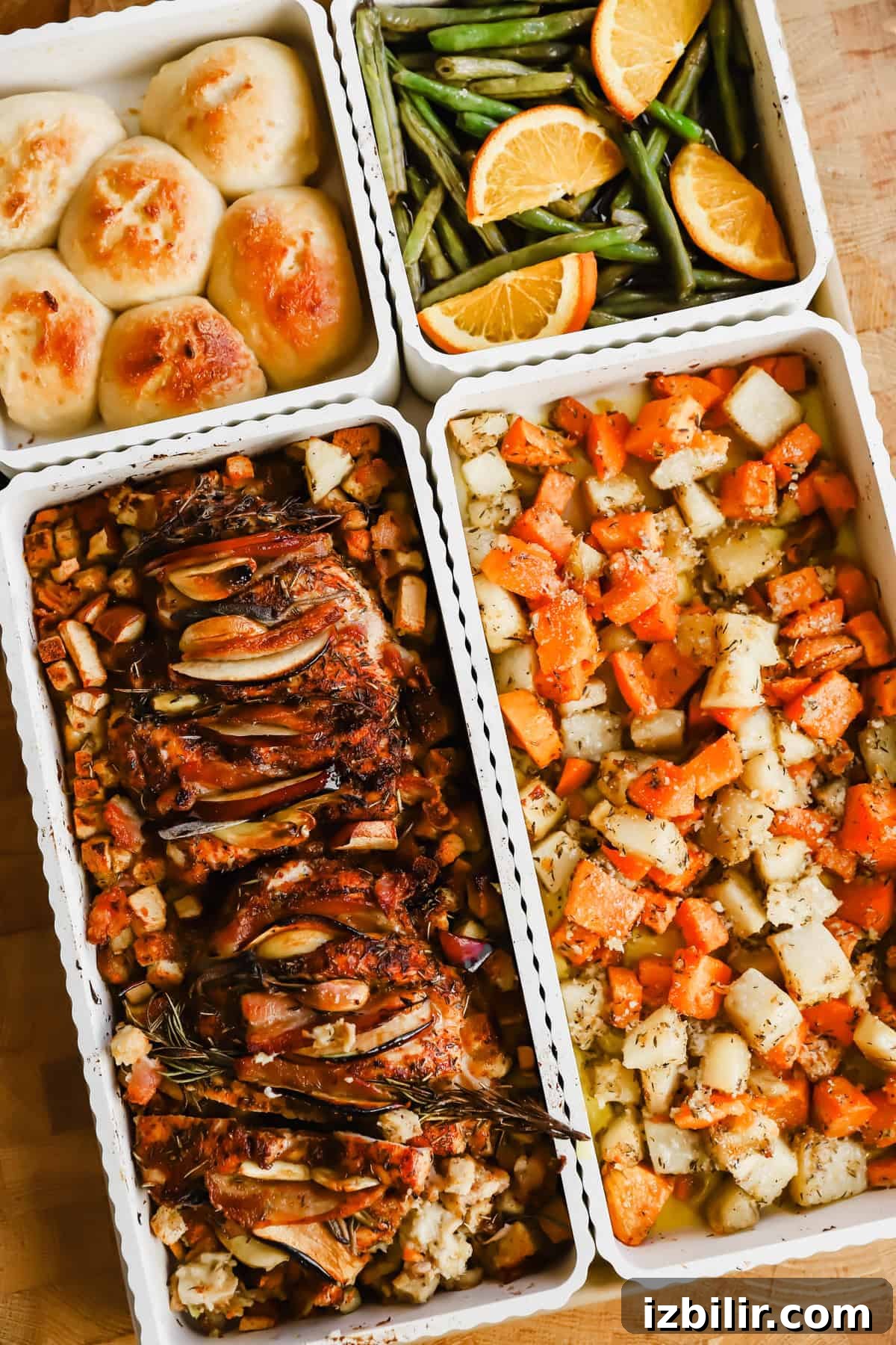 Sheet-Pan Thanksgiving Dinner for 4: Complete One-Tray Menu 2 Four trays of food including dinner rolls, green beans with orange slices, roasted meat with herbs and vegetables, and a mix of roasted potatoes and carrots.