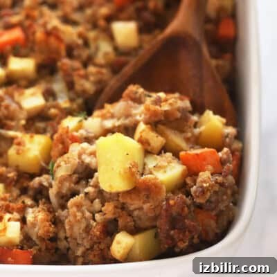 Thanksgiving Sides Worth Serving (Everything But Turkey) 25 Sausage stuffing in a white baking dish with a wood spoon.