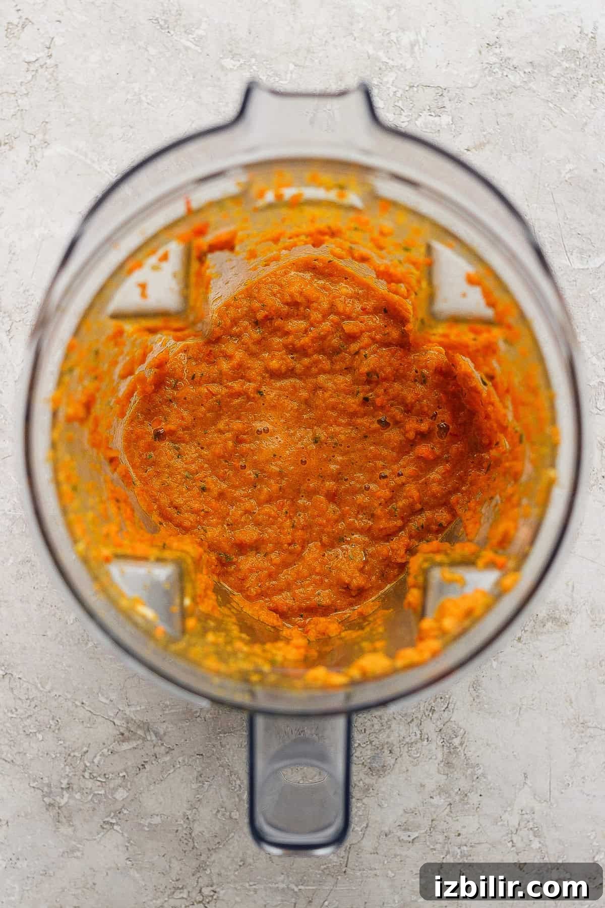 Comforting Soup to Boost Immunity 4 A blender with orange vegetable puree inside, viewed from above on a light-colored surface.