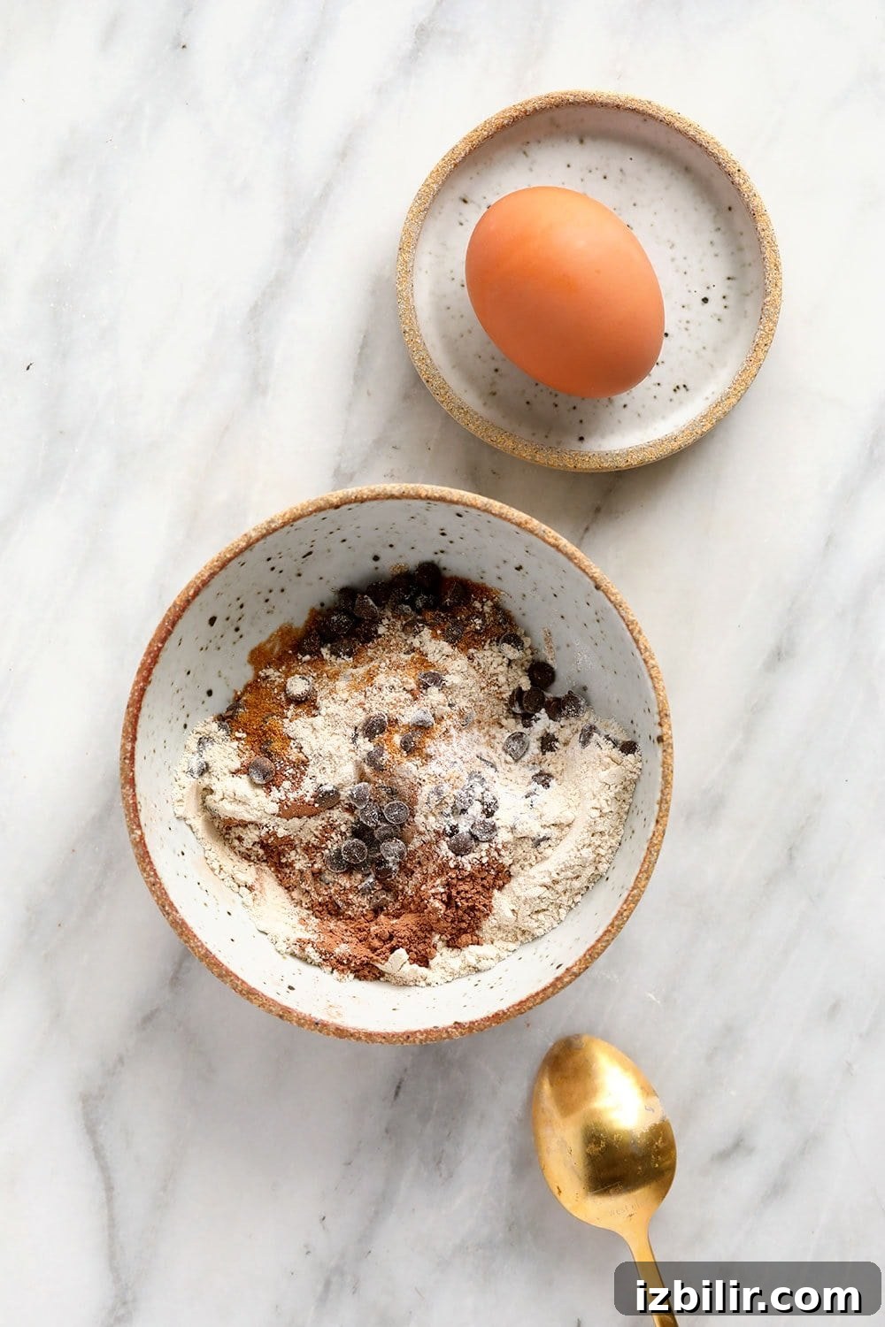 chocolate mug cake dry ingredients in a bowl with an egg ready to be cracked into the mix