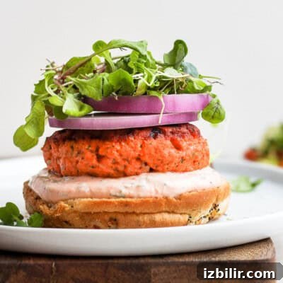 10 High-Protein Spring Recipes to Refresh Your Menu 5 Delicious salmon burgers served with arugula and red onion on a white plate.