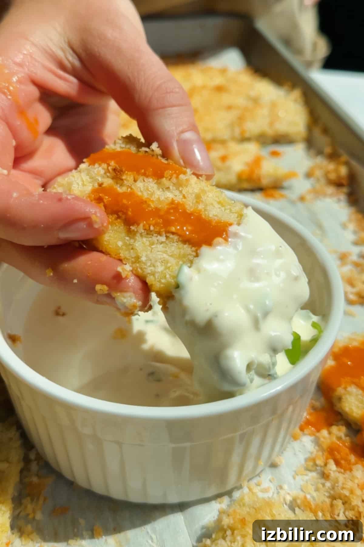 Dipping a buffalo-sauced chicken protein bar into creamy blue cheese dressing