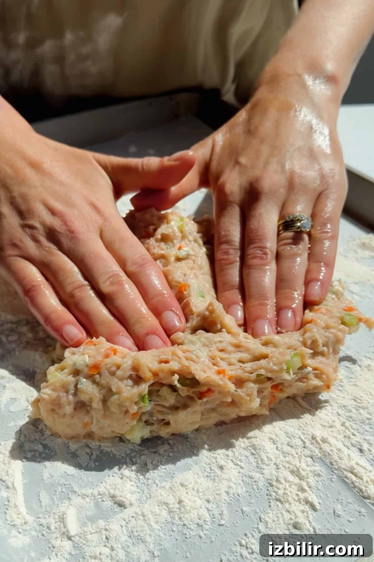 Pressing and shaping ground chicken protein bar mixture with vegetables on parchment paper