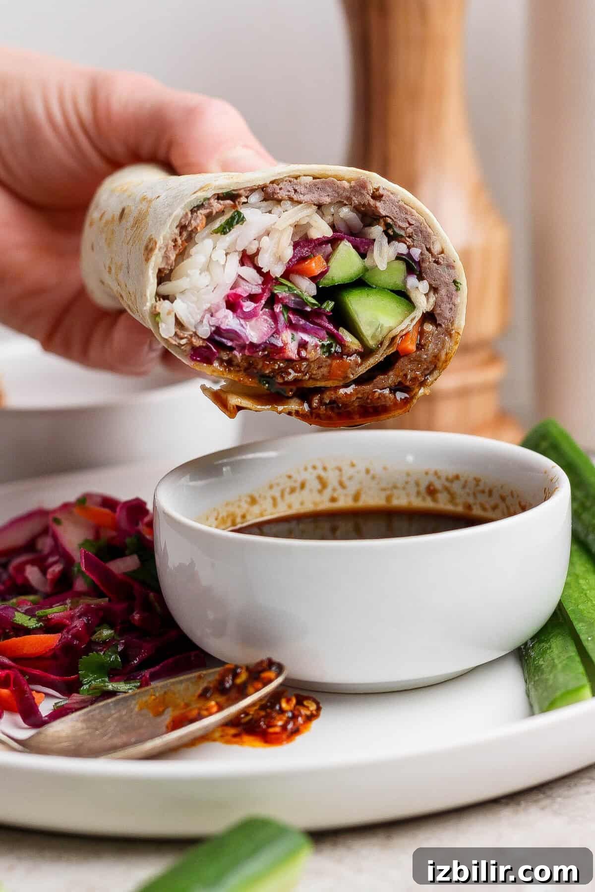 Partially eaten wrap filled with rice, vegetables, and sauce