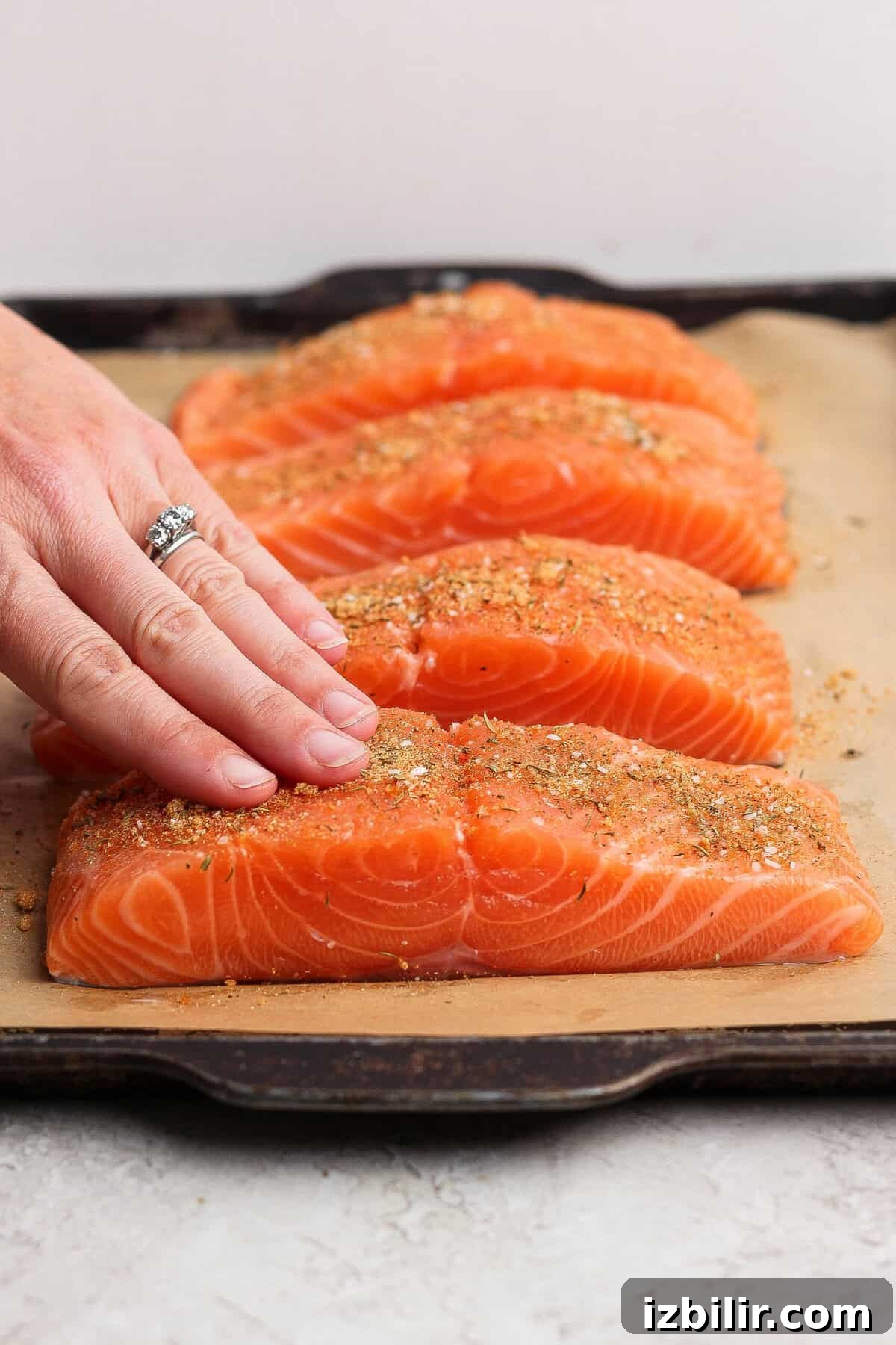 8-Minute Broiled Salmon with Simple Seasoning 4 Rubbing seasoning onto raw salmon fillets on a parchment-lined baking sheet.