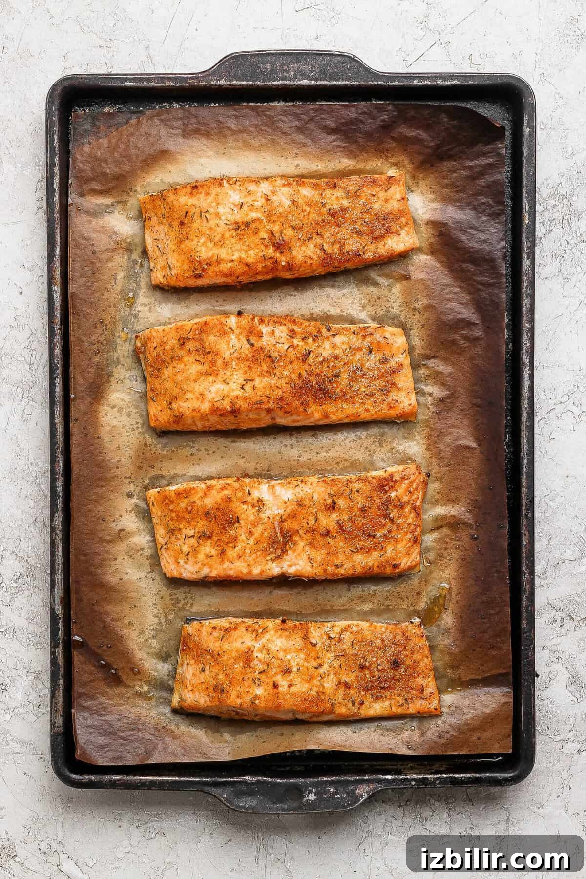 8-Minute Broiled Salmon with Simple Seasoning 6 Four golden broiled salmon fillets on a parchment-lined baking sheet fresh from the oven.