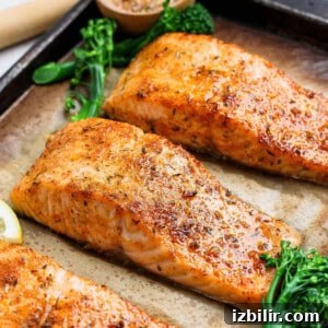8-Minute Broiled Salmon with Simple Seasoning 8 Three golden broiled salmon fillets on a parchment-lined baking sheet with broccolini and lemon.