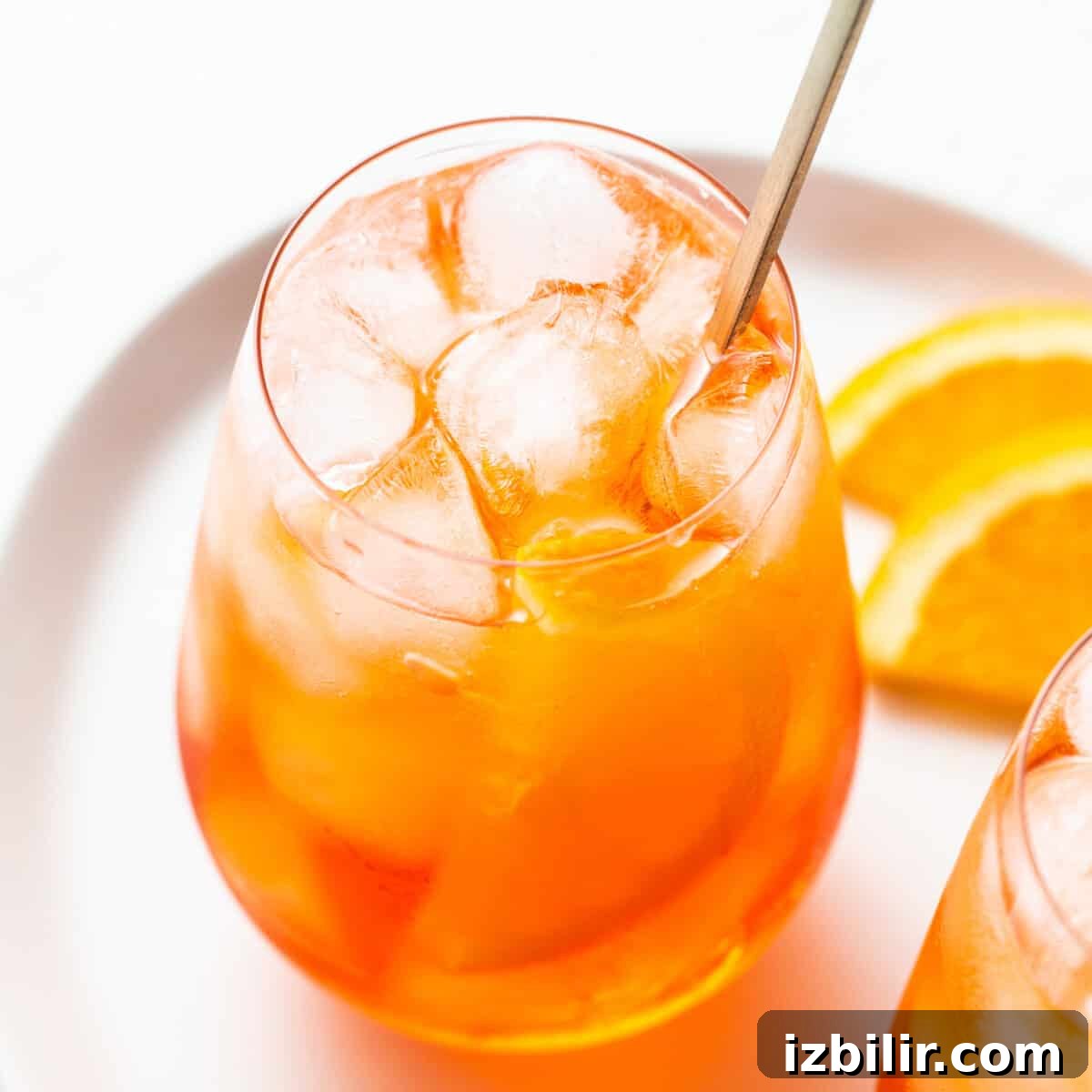 Aperol spritz in a glass with a straw.