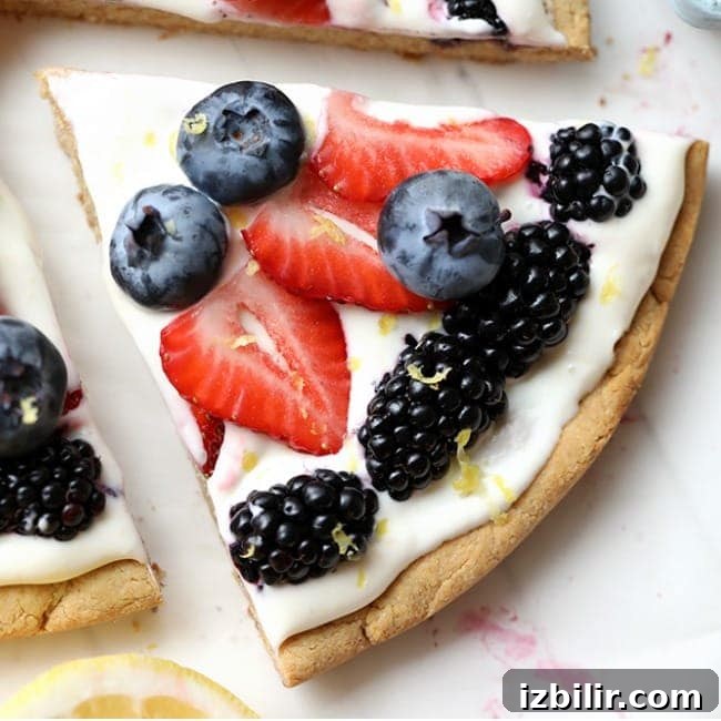 A slice of pizza with berries and lemon on it.