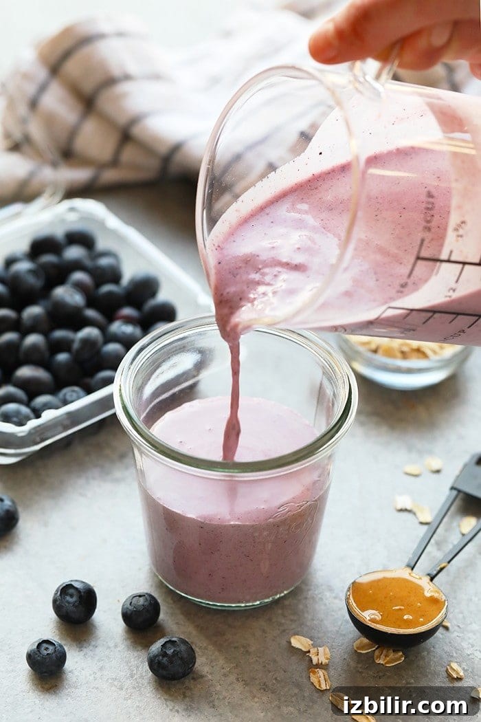 Creamy Peanut Butter and Jelly Smoothie Recipe 5 pouring smoothie into glass.