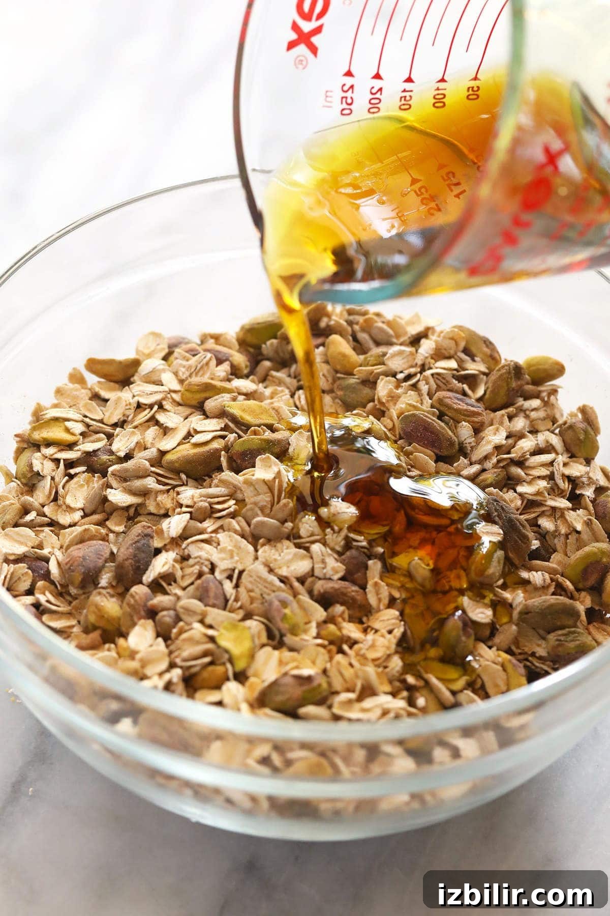 Homemade Pistachio Cherry Granola 4 Pouring maple syrup over the granola ingredients.