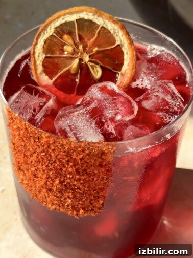 Glass pitcher of Agua de Jamaica with orange slices