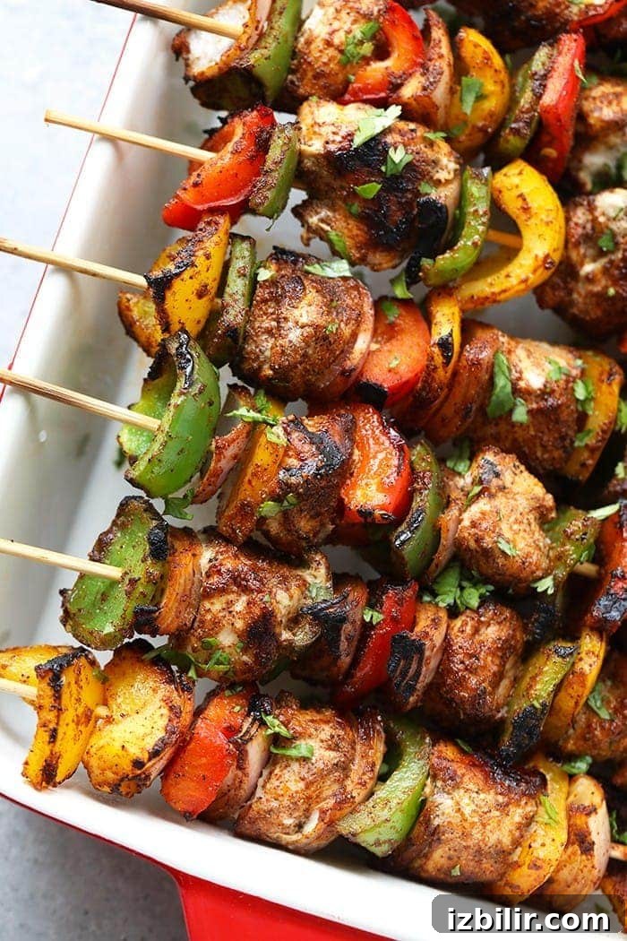 Juicy grilled chicken fajita kabobs are ready in less than 30 minutes! Made with lean chicken breast, peppers, onions, and an easy homemade fajita seasoning. chicken fajita kabobs in casserole dish.