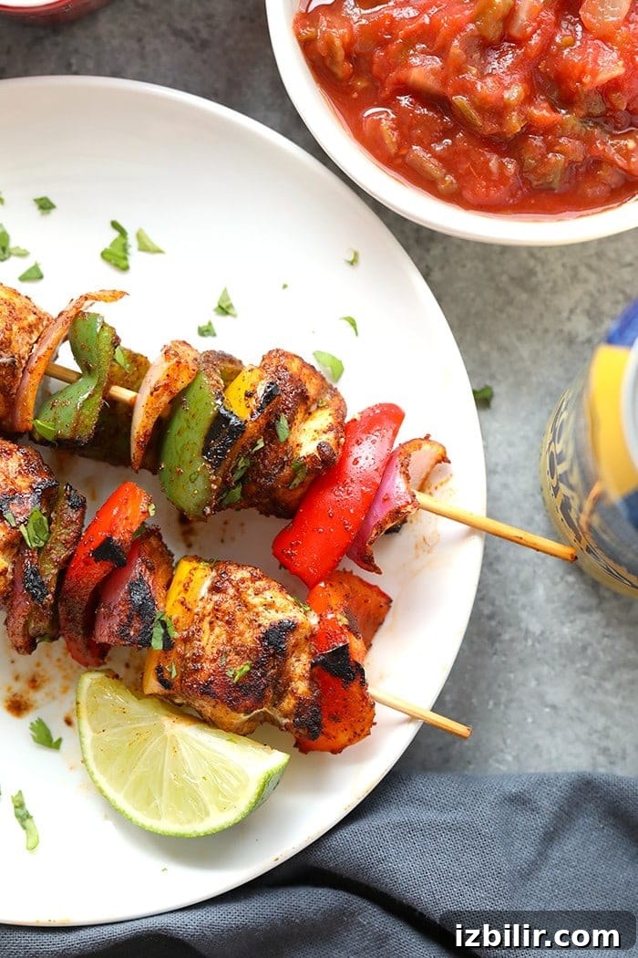 Squeeze fresh lime and sprinkle cilantro on finished kabobs for a bright finish. chicken fajita kabobs on plate.