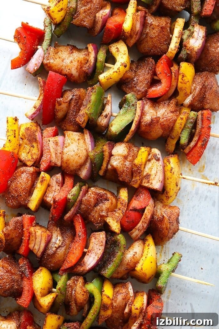 Prep your chicken and vegetables into even 1-inch pieces for quick and even cooking. raw chicken kabobs on countertop with spices.